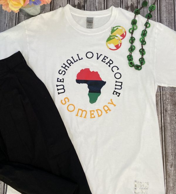 white tshirt with red, green, and black Africa encircled with by the words "We Shall Overcome Someday" and other fashion accesories